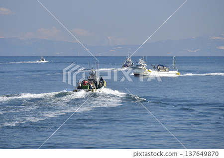 A photograph of fishing boats coming and going in Funka Bay off the coast of Yakumo Town, Hokkaido, in early spring. 137649870