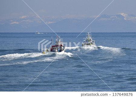 A photograph of fishing boats coming and going in Funka Bay off the coast of Yakumo Town, Hokkaido, in early spring. 137649876