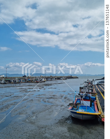 A beach where fishing boats are anchored. 137651148