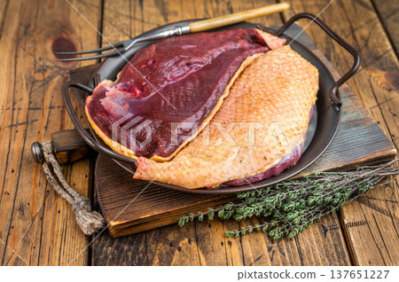 Raw duck meat breast with fat and skin in pan with herbs. Gamebird poultry game meat food still life on wooden background.. Raw duck meat breast with fat and skin in pan with herbs. Gamebird poultry game meat food still life on wooden background.. 137651227