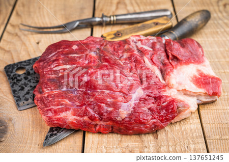 Raw beef brisket on rustic wooden table with butcher tools, overhead meat preparation scene with copy space 137651245