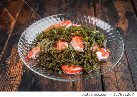 Sea grapes salad with imitation crab sticks on glass plate over dark wooden background Asian seafood dish top view Sea grapes salad with imitation crab sticks on glass plate over dark wooden background Asian seafood dish top view 137651267