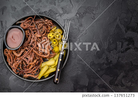 Pulled beef brisket with barbecue sauce, pickles and jalapeno in skillet on dark background, top view with copy space.. 137651273