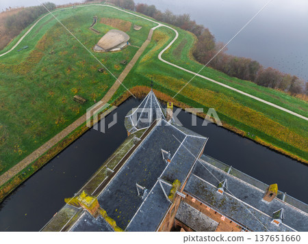 Top-down aerial view of the medieval Muiderslot castle courtyard and towers. Close-up drone shot of the historic fortress, moat, and formal gardens in Muiden, Netherlands, on a misty day. Top-down aerial view of the medieval Muiderslot castle courtyard and towers. Close-up drone shot of the historic fortress, moat, and formal gardens in Muiden, Netherlands, on a misty day. 137651660