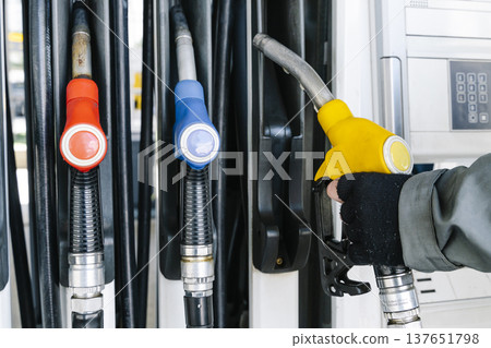 Fuel pump nozzles hanging at a modern gas station during a period of high oil prices. A conceptual photography showcasing the global energy crisis, increasing gasoline costs 137651798