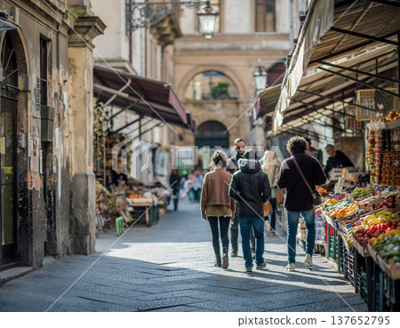 Group walks through market in city at mid-day while vendors display fresh produce and goods for sale Group walks through market in city at mid-day while vendors display fresh produce and goods for sale 137652795
