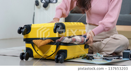 Travel Preparation. Woman packing yellow suitcase with clothes and accessories for vacation. Travel Preparation. Woman packing yellow suitcase with clothes and accessories for vacation. 137653203