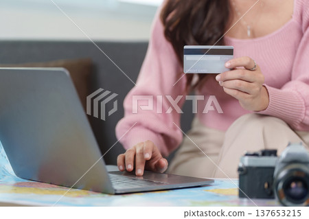 Online Booking. Woman using laptop for travel arrangements with credit card. 137653215