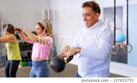 Group of people exercising with kettlebells in gym 137653755