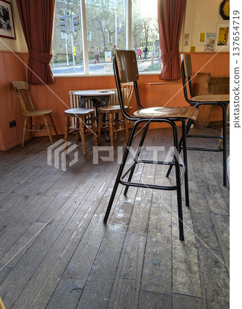 Warm and inviting bar scene with a British-style pub interior, complete with wooden paneling, old-fashioned decor, and a welcoming feel with stools and wooden floor Warm and inviting bar scene with a British-style pub interior, complete with wooden paneling, old-fashioned decor, and a welcoming feel with stools and wooden floor 137654719