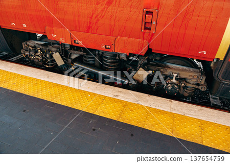 Train wheels and undercarriage view at a busy railway station during the day Train wheels and undercarriage view at a busy railway station during the day 137654759