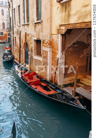 Gondola parked in canal by old buildings in Venice during sunny day 137654808