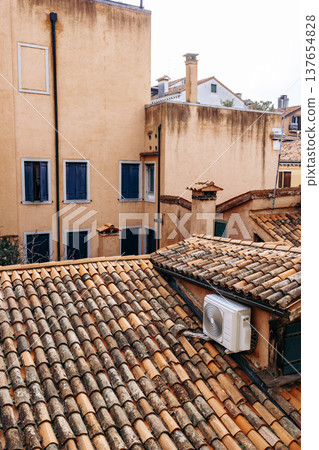 Rooftop view of buildings and air conditioning unit in a quiet city area during the daytime 137654828
