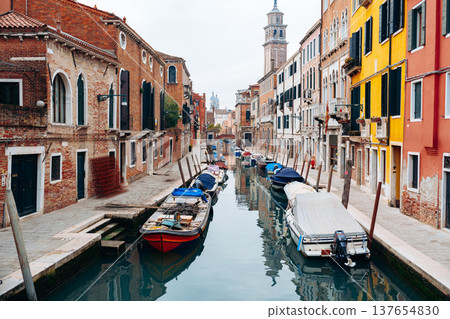 Quiet canal in Venice with boats and colorful buildings in the background near evening sky Quiet canal in Venice with boats and colorful buildings in the background near evening sky 137654830