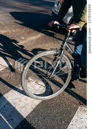 Person rides a bicycle on the street during daylight hours in an urban area Person rides a bicycle on the street during daylight hours in an urban area 137654844