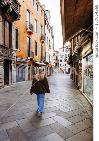 Woman walks in quiet street in Venice during daytime Woman walks in quiet street in Venice during daytime 137654969