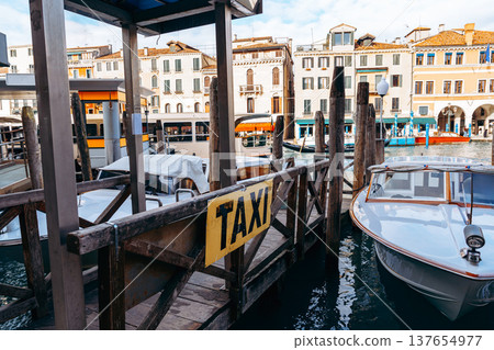 Water taxi dock by buildings in a busy canal during a clear day in a coastal town Water taxi dock by buildings in a busy canal during a clear day in a coastal town 137654977