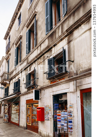 Building with balconies and a post box in a street with shops in a city 137654993