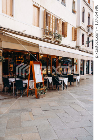 Outdoor dining area in a city with empty tables and a menu board during the day 137654996
