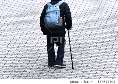 一位拄著拐杖（戴口罩）的老人在日本橫濱。天氣寒冷……雖然已是三月，但寒意卻再次襲來……人生究竟是怎樣一番景象……？ = 橫濱市 137655103