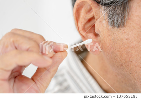 一位老人在用棉花棒清潔耳朵 137655183