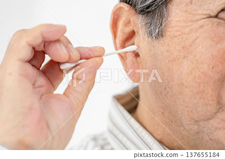 Senior man cleaning his ears with a cotton swab Senior man cleaning his ears with a cotton swab 137655184