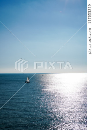 A yacht floating on the sea with the horizon sparkling in the sunlight. 137655239
