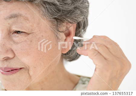 一位老婦人正在用棉花棒清潔耳朵。 137655317