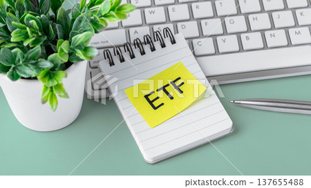ETF message on notebook with computer keyboard and pen on green table with small plant, etf investment concept ETF message on notebook with computer keyboard and pen on green table with small plant, etf investment concept 137655488