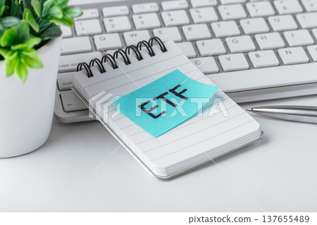ETF sticky note on notebook with computer keyboard and pen on work table, etf investment concept, closeup 137655489