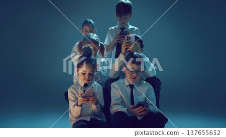Children using smartphones together in neon studio symbolizing digital dependence 137655652