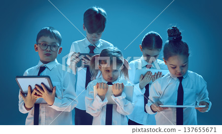 Children concentrating on tablet screens in neon studio symbolizing digital future lifestyle Children concentrating on tablet screens in neon studio symbolizing digital future lifestyle 137655671