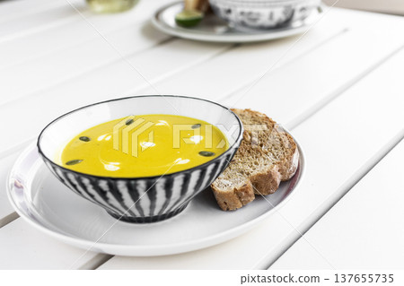 yellow organic pumpkin soup bowl with sourdough toast on restaurant white table outddor yellow organic pumpkin soup bowl with sourdough toast on restaurant white table outddor 137655735