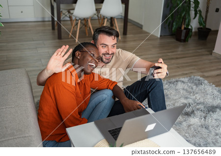 Happy couple video calling family and friends using laptop and smartphone at home Happy couple video calling family and friends using laptop and smartphone at home 137656489