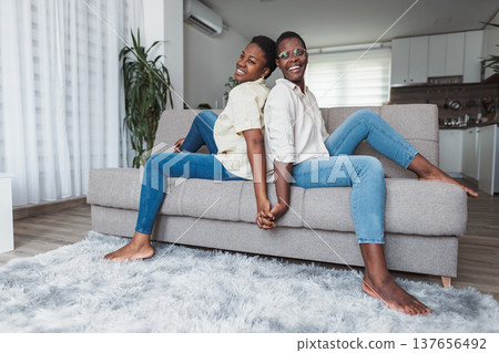 Two Young Women Holding Hands and Relaxing on Sofa at Home Two Young Women Holding Hands and Relaxing on Sofa at Home 137656492