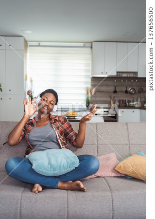 Young woman enjoying music with headphones in living room 137656500