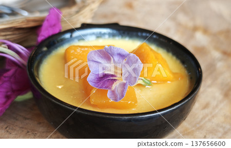 A mango mousse pudding in a cup sits on a table in the cafe. 137656600