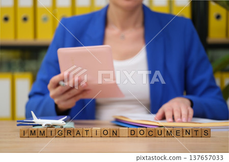 Preparing important immigration documents while seated at an organized desk with a model airplane Preparing important immigration documents while seated at an organized desk with a model airplane 137657033