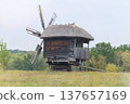 Old wooden mill. Authentic house in vintage style. Installation in museums of traditional retro style. Windmill. Sunny day. 137657169