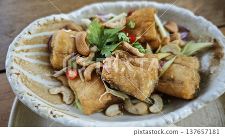 Crispy fried sea bass with a rich, spicy and sour spiced sauce and herbs. Crispy fried sea bass with a rich, spicy and sour spiced sauce and herbs. 137657181