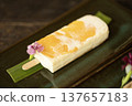 Plum marian flavored ice cream with cream cheese, white chocolate, and cracker base, with peanut butter, served on a stick. 137657183