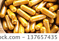Herbal capsules containing turmeric powder in a wooden bowl. A natural anti-inflammatory dietary supplement. 137657435