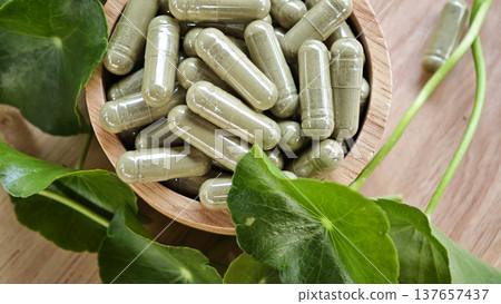 Herbal capsules containing Centella asiatica powder in a wooden bowl. A natural dietary supplement. 137657437