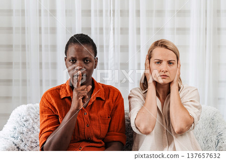 Woman making silence gesture and another covering ears 137657632
