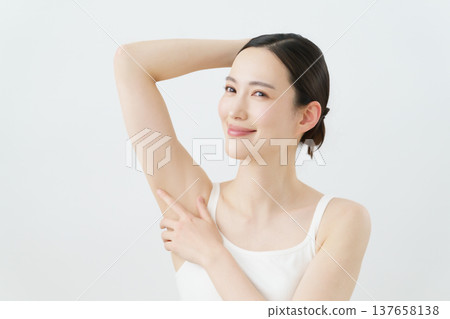 一位年輕的日本女性面帶微笑，一隻手放在身體一側，背景為白色；脫毛圖片。 137658138