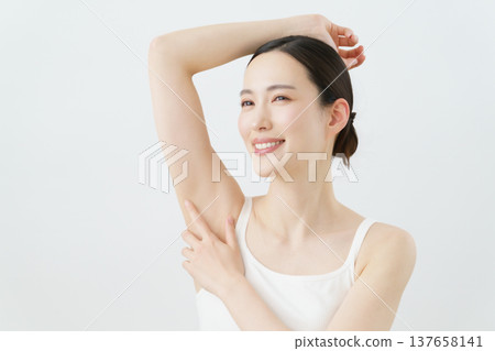 A young Japanese woman smiles with her hand on her side against a white background; hair removal image. A young Japanese woman smiles with her hand on her side against a white background; hair removal image. 137658141