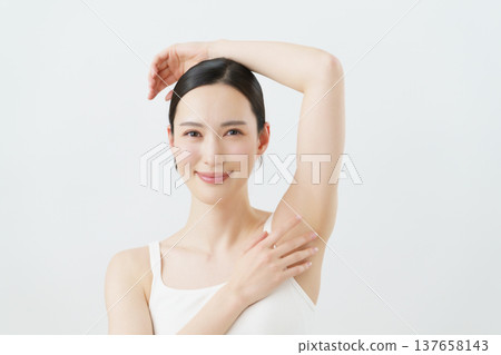 一位年輕的日本女性面帶微笑,一隻手放在身體一側,背景為白色;脫毛圖片。 一位年輕的日本女性面帶微笑,一隻手放在身體一側,背景為白色;脫毛圖片。 137658143