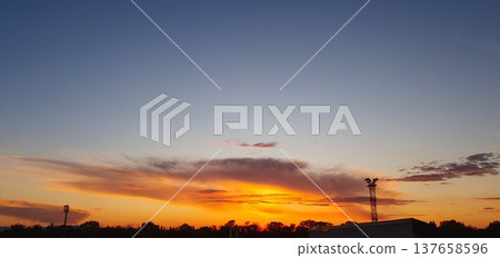 Phone photo of an orange and blue sunset with textured clouds. Dramatic evening sky showing color contrast, weather patterns, and calm outdoor atmosphere. 137658596