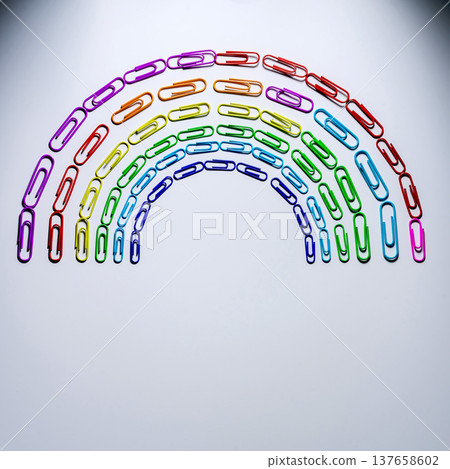 Colorful paper clips arranged in a rainbow shape on a white surface during daytime 137658602