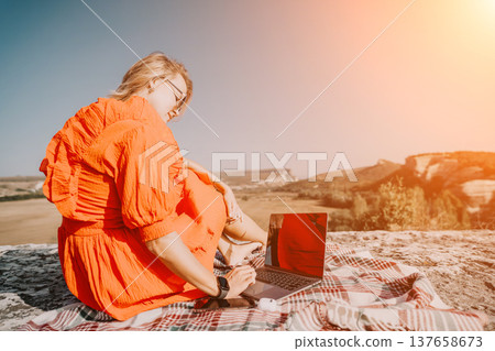 Young Woman in Orange Dress Working on Laptop in Nature Young Woman in Orange Dress Working on Laptop in Nature 137658673